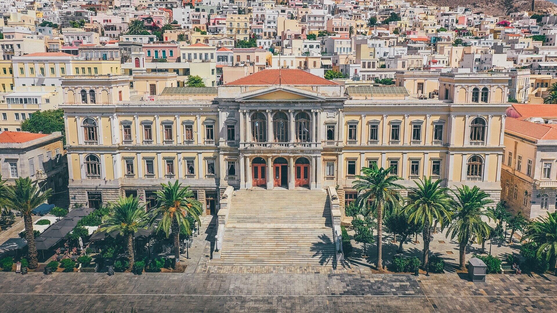 A large, classical building with a symmetrical facade, multiple windows, and a central entrance with steps leading up to it.