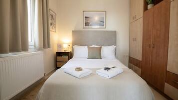 A hotel room with a bed, a nightstand, a framed picture on the wall, and a wardrobe.