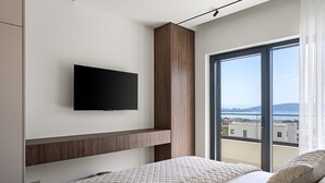 Een moderne slaapkamer met een bed, een tv aan de muur en een groot raam met uitzicht op de stad.