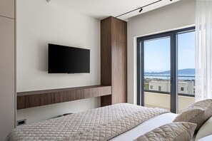 Ein modernes Schlafzimmer mit einem Bett, einem an der Wand montierten Fernseher und einem großen Fenster mit Blick auf die Stadt.