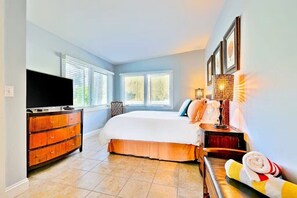 Un dormitorio con cama, televisor, cómoda y ventana.