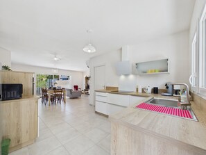 Una cocina moderna con encimera de madera, un lavabo y un comedor con sillas y una mesa.