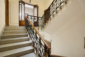 A staircase with a wooden handrail and black metal balusters, leading to a door with a glass panel. - La Dimora Dei Reali - Bordeaux Suite with Private Terrace (Naples)