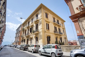 A multi-story building with a classic architectural style, featuring balconies with railings and potted plants. - La Dimora Dei Reali - Bordeaux Suite with Private Terrace (Naples)