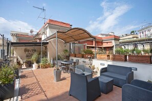 A rooftop patio with outdoor furniture, potted plants, and a pergola providing shade. - La Dimora Dei Reali - Bordeaux Suite with Private Terrace (Naples)