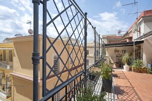 A courtyard with a metal fence, potted plants, and buildings with balconies. - La Dimora Dei Reali - Bordeaux Suite with Private Terrace (Naples)