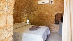 A stone-walled room with a bed, a bedside lamp, and a small table with a lamp. - Villa 'Tenuta Rosa in Salento' with Private Terrace, Private Garden and Air Conditioning (Taviano)