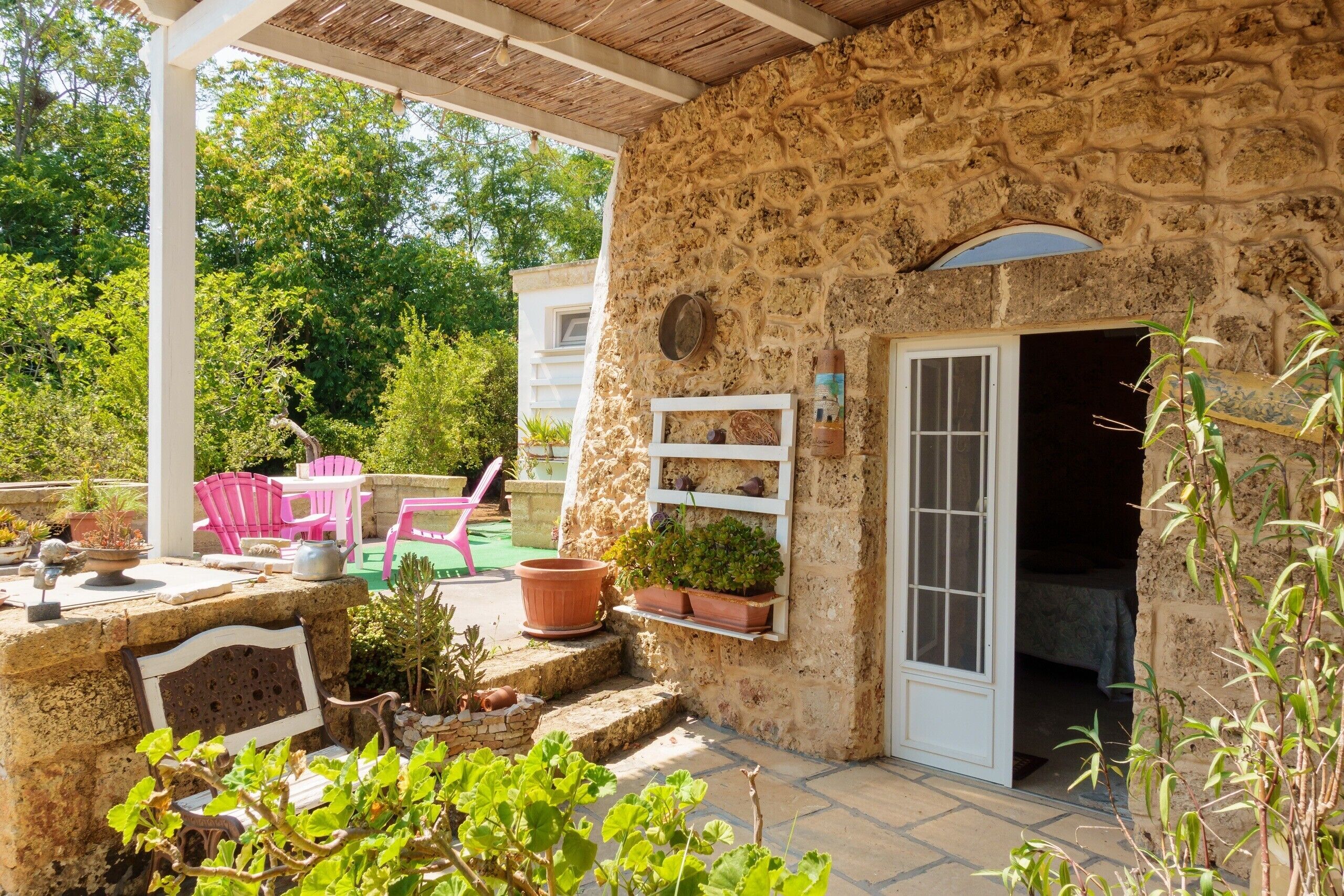 A stone building with a covered patio, outdoor seating, and potted plants.