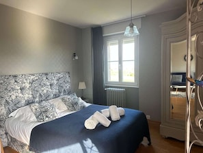 Une chambre avec un grand lit, une fenêtre, un radiateur et un miroir.