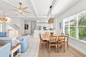 Eine moderne Küche mit weißen Schränken, ein Essbereich mit Holztisch und Stühlen sowie ein Deckenventilator.