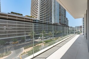 Un bâtiment moderne doté d’une façade en verre, d’un balcon donnant sur la rue et, en arrière-plan, de bâtiments de grande hauteur.