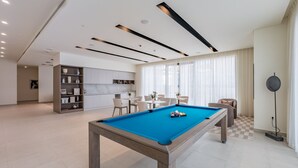 Una sala de estar moderna con mesa de billar, una zona de cocina y un comedor.