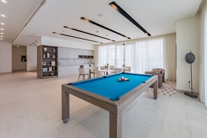 Ein modernes Wohnzimmer mit Billardtisch, Küchenbereich und Essplatz.