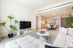 Un salon moderne doté d’un téléviseur à écran plat, d’un canapé et d’un coin repas avec des chaises et une table.