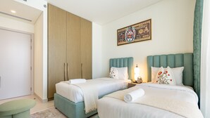 Habitación de hotel con dos camas, un armario, un cuadro y un reloj.
