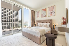 Una habitació d'hotel amb un llit gran, un escriptori, una cadira, vista a un paisatge urbà i obra d'art a la paret.