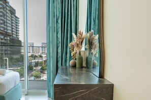 Ein modernes Wohnzimmer mit einem Marmorkonsolentisch, einer Couch und Blick auf eine Skyline durch große Fenster.