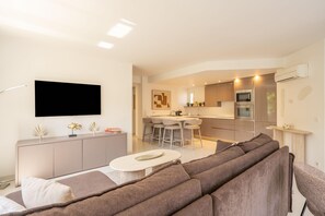 A modern living room with a sofa, a coffee table, and a flat-screen TV mounted on the wall.