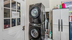 A laundry area with stacked washers and dryers, a cabinet with cleaning supplies, and a door with a 'DO NOT ENTER' sign. - Pet-Friendly Above Garage Suite - Shared Hot Tub (Clarendon)