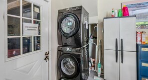 A laundry area with stacked washers and dryers, a cabinet with cleaning supplies, and a door with a 'DO NOT ENTER' sign. - Pet-Friendly Above Garage Suite - Shared Hot Tub (Clarendon)