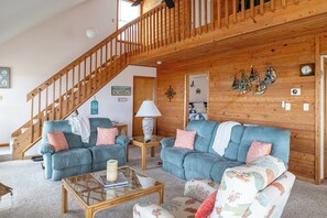 A cozy living room with a wooden staircase, two sofas, a coffee table, and a lamp. - Blue Horizon - Oceanfront Home (Atlantic Beach)
