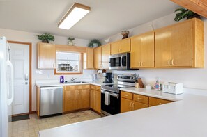 Uma cozinha moderna com armários de madeira, eletrodomésticos de aço inoxidável e uma janela com vista para uma casa.