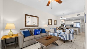 A living room with a sofa, armchairs, a coffee table, and a ceiling fan. - Ocean Breeze! 5th Floor 2BR Gulf-Front Condo Sleeps 6 (Panama City Beach)