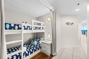 A child's bedroom with bunk beds, a nightstand, and a wall decoration. - Ocean Breeze! 5th Floor 2BR Gulf-Front Condo Sleeps 6 (Panama City Beach)