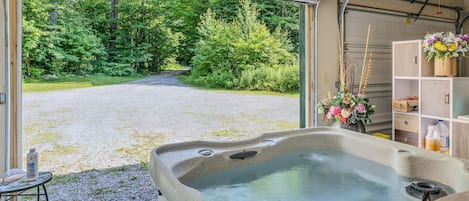 Un bain à remous avec vue sur un chemin de gravier menant à une forêt.