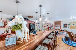 A modern kitchen with wooden cabinets, a long countertop, and pendant lighting. - Country Suite | Large Deck, Hot Tub, Pet Friendly (Clarendon)
