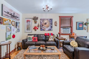 Ein Wohnzimmer mit Ledersofa, Couchtisch und verschiedenen Wandbildern.