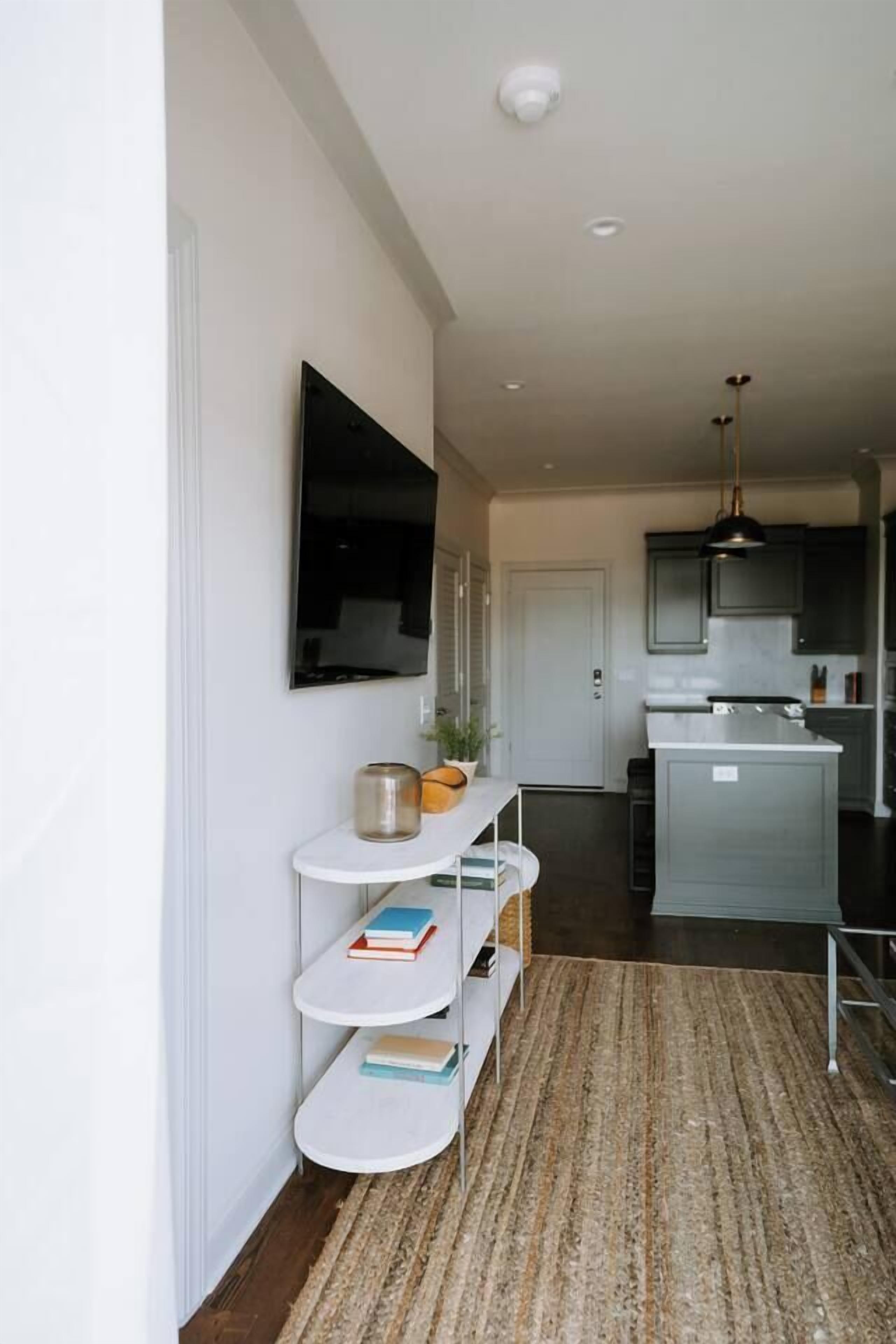 A modern kitchen with grey cabinets, a white countertop, and a hanging pendant light.