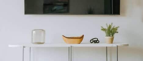A white TV stand with shelves holding books and a bowl.