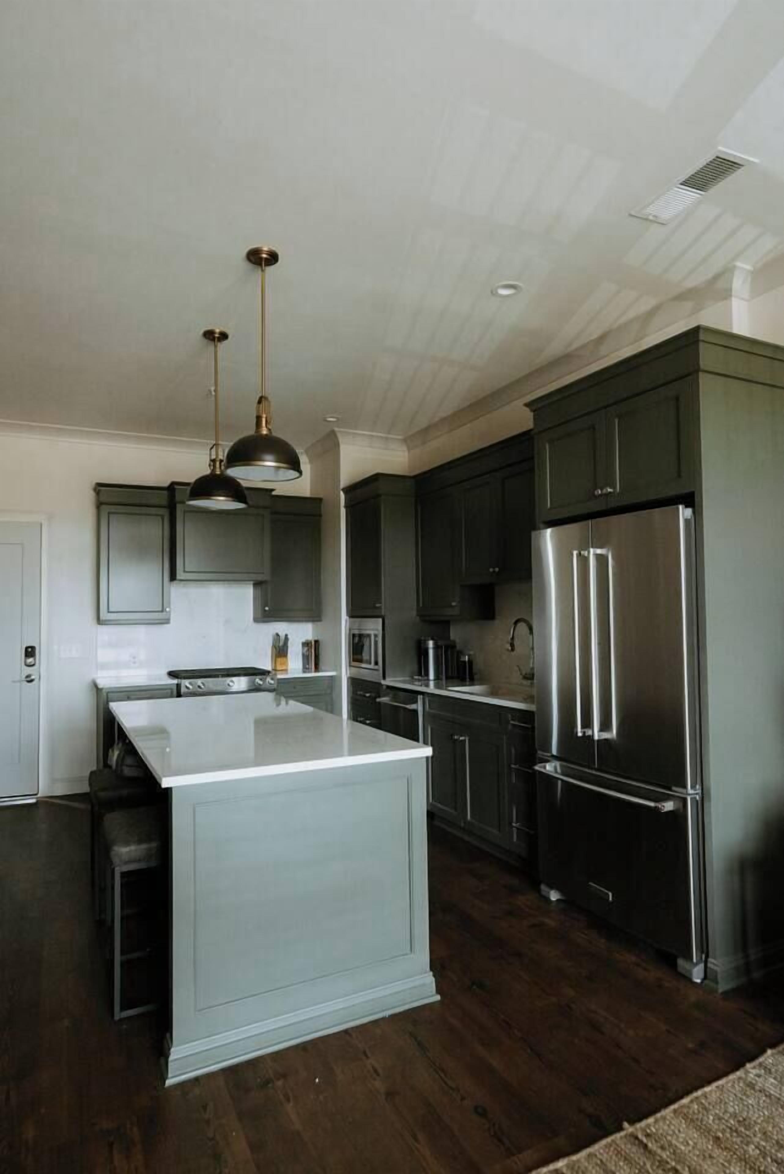 A modern kitchen with dark cabinetry, stainless steel appliances, and a central island.