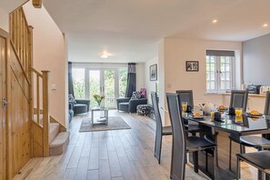 A modern interior with a dining area, a staircase, and a view of the outdoors. - Charming Dorset Coach House for 6 (Lyme Regis)