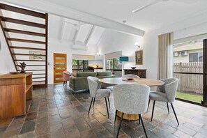 Een ruime woonkamer met een eettafel, zithoek en uitzicht op de omgeving.