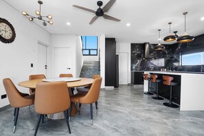 A modern kitchen with a marble countertop, a ceiling fan, and a dining area with a round table and chairs.