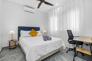 Une chambre d’hôtel équipée d’un lit, d’un bureau, d’une chaise, d’un ventilateur de plafond et d’un appareil de climatisation.