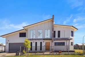 A modern two-story house with a garage, a fenced yard, and a clear blue sky.