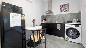 Ett modernt kök med en inbyggd tvättmaskin, ett matbord med stolar och en dekorativ vas.