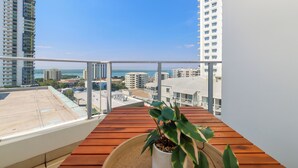 Ein Balkon mit Holzboden, einem Blumentopf und Blick auf Stadt und Wasser.