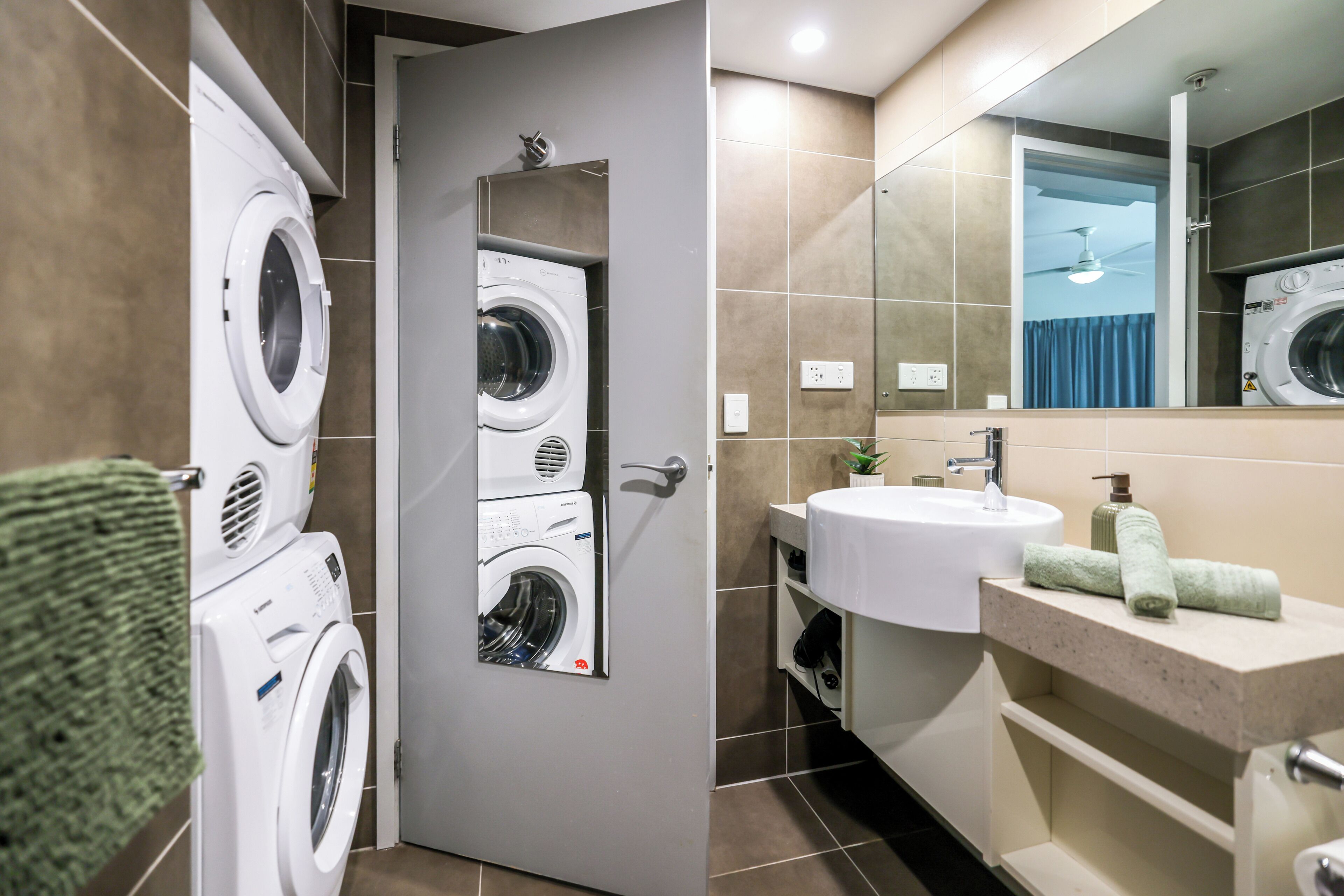 A modern bathroom with a built-in washer and dryer, a sink, and a mirror.