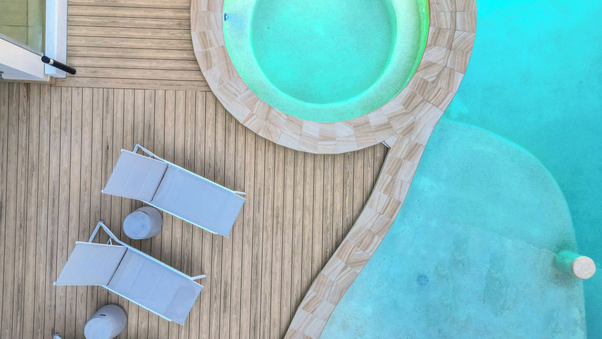 A wooden deck with a circular pool, two lounge chairs, and a small table.