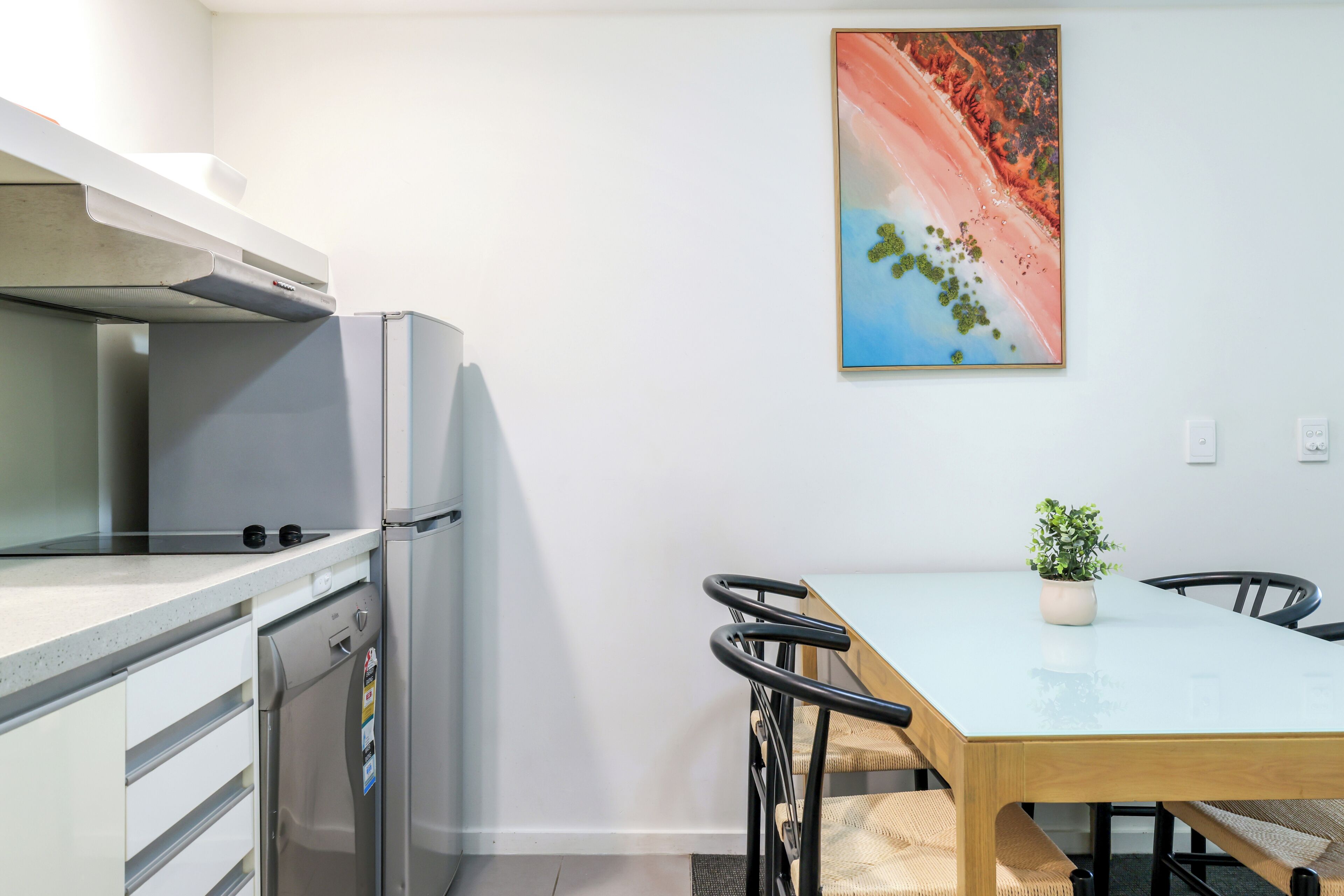 A modern kitchen with a refrigerator, stove, and a dining table with chairs.