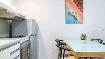 A modern kitchen with a refrigerator, stove, and a dining table with chairs.
