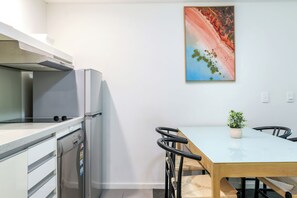Una cocina moderna con refrigerador, estufa y una mesa de comedor con sillas.