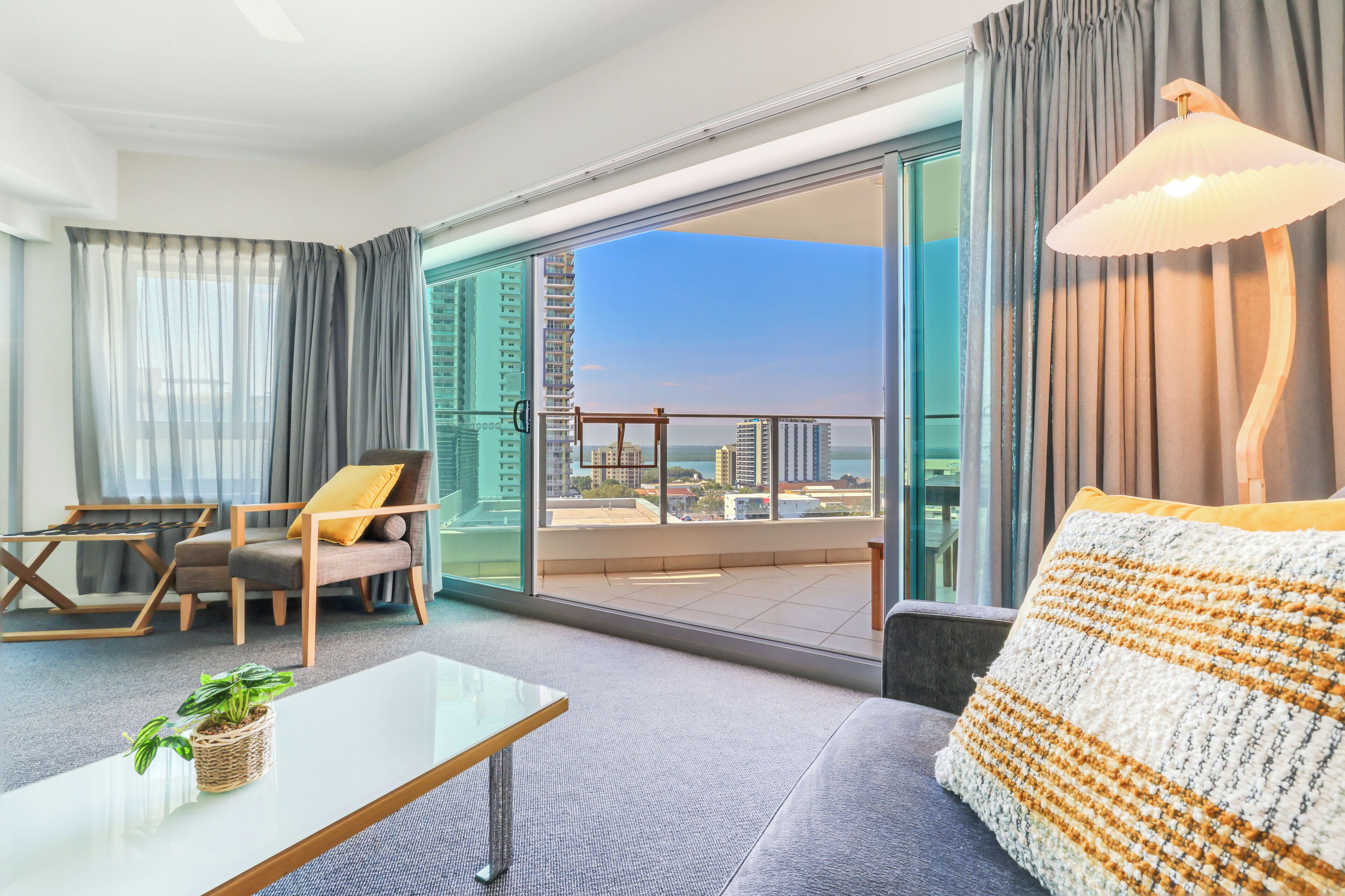 Ein modernes Hotelzimmer mit Balkon, einer Couch, einem Sessel, einem Couchtisch und Blick auf die Stadt.