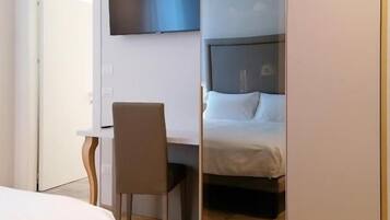Una habitación de hotel con cama, escritorio, silla, televisor y armario.