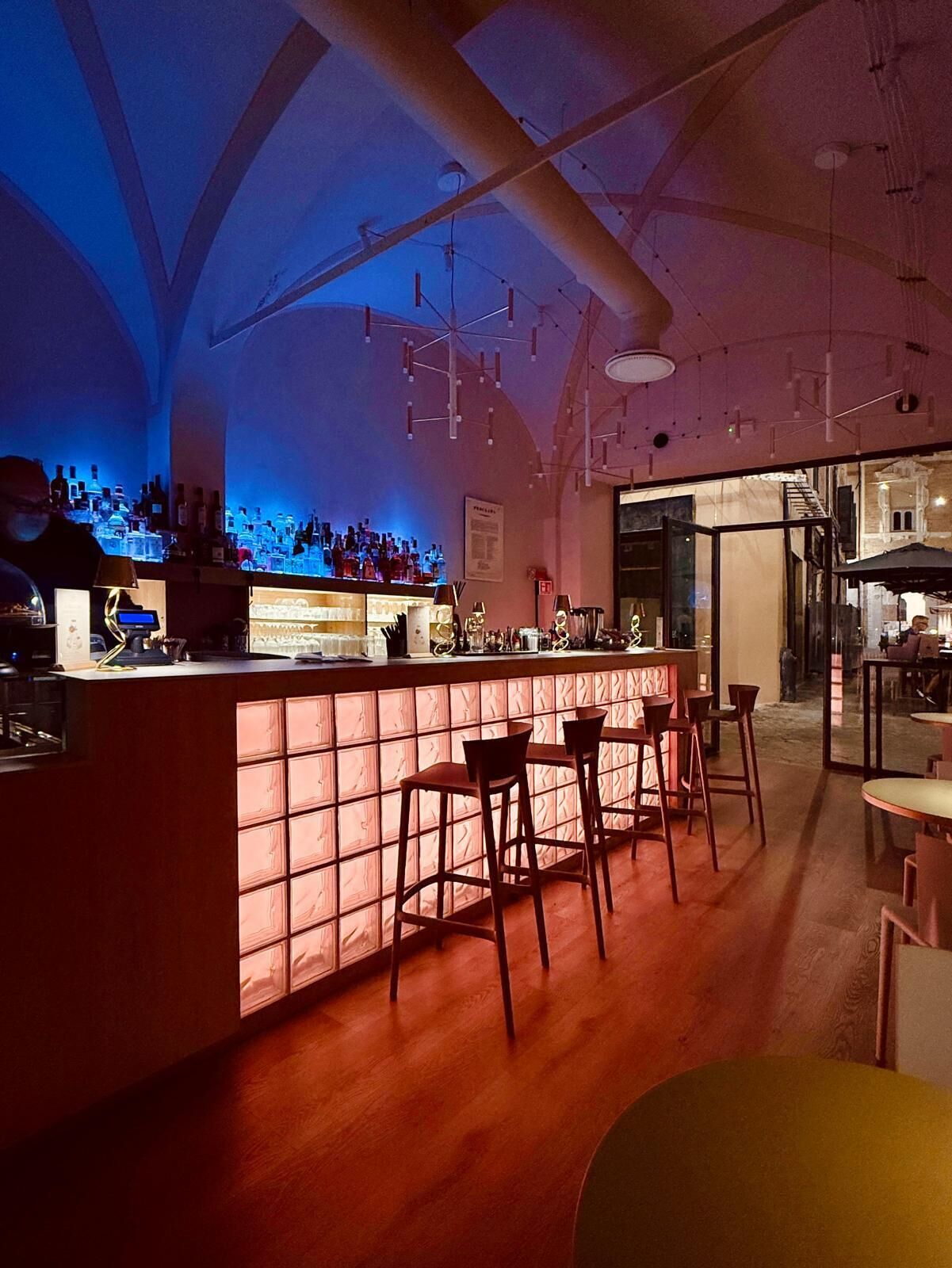 Angolo bar con bancone, sgabelli e vista sull'adiacente sala da pranzo.