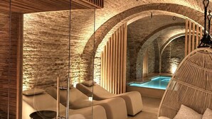 Un espacio de spa con pared de piedra, techo de madera y una silla colgante.